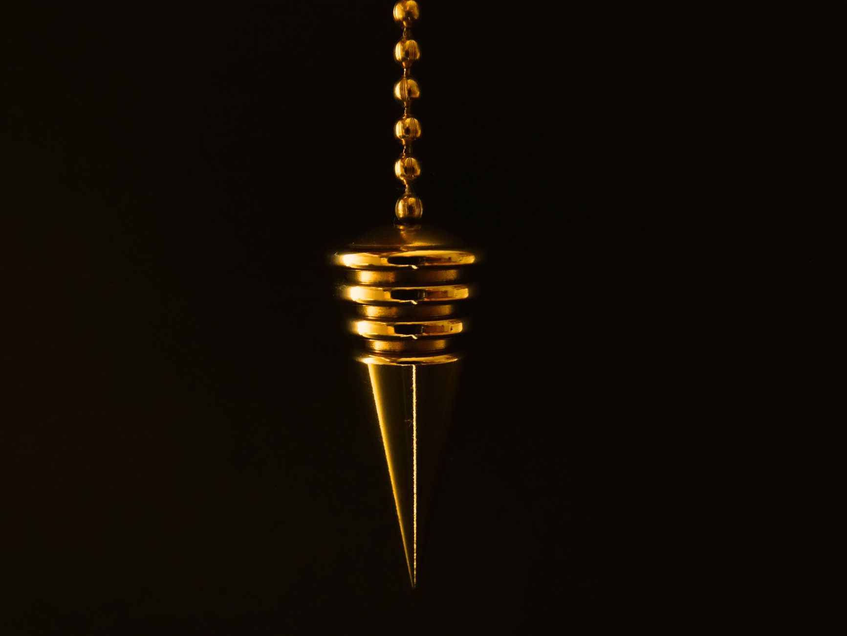 Pendule ou chaine doree sur fond sombre.