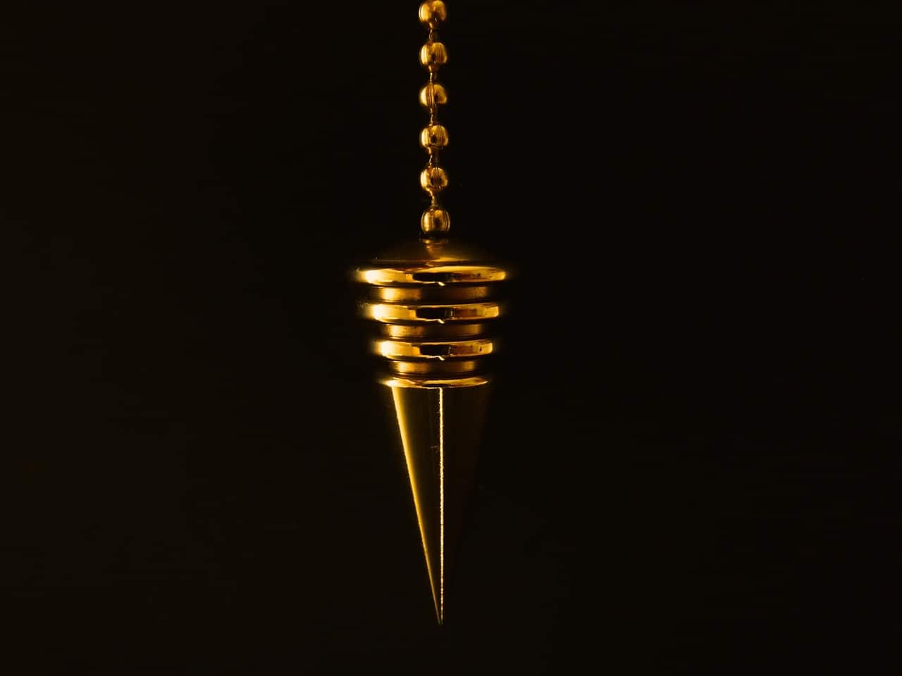 Pendule ou chaine doree sur fond sombre.