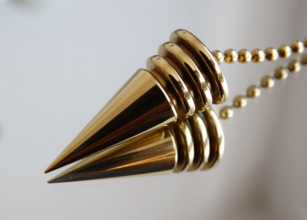 Pendule ou chaine doree sur fond sombre.